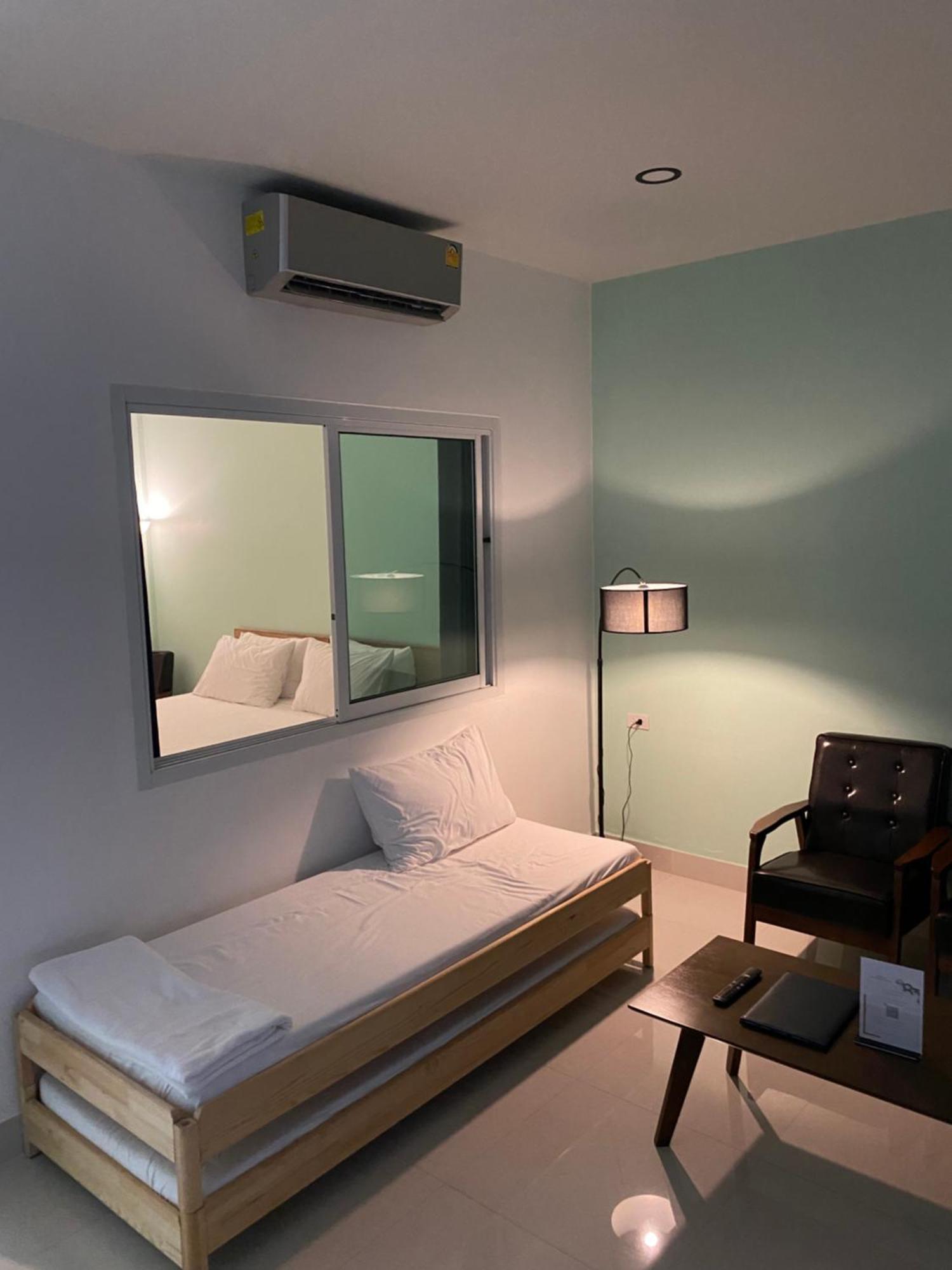 Minimalist guest room with a wooden daybed, air conditioning, a large window and a lounge chair