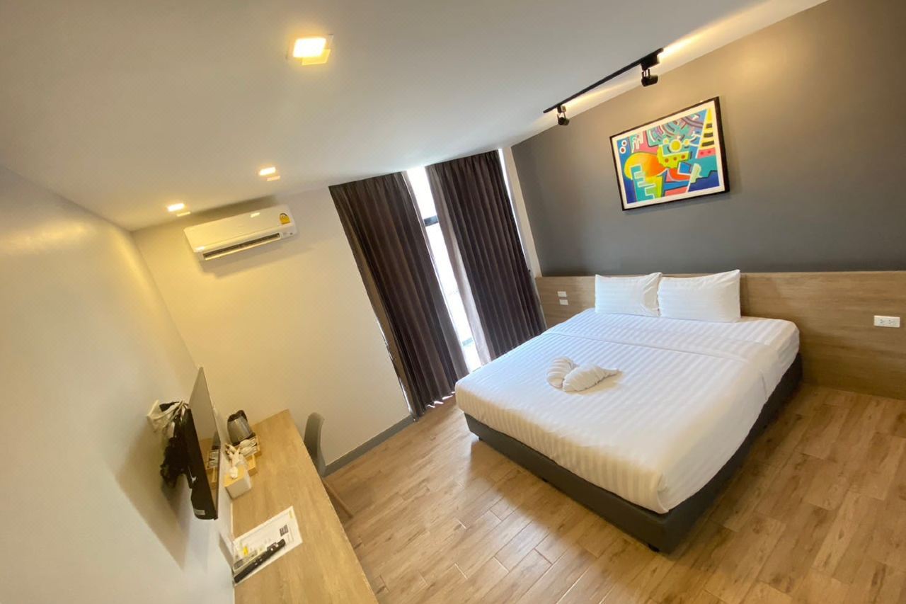 King room with wood floor, bright artwork, AC and a work desk at The Model Garden Yasothon