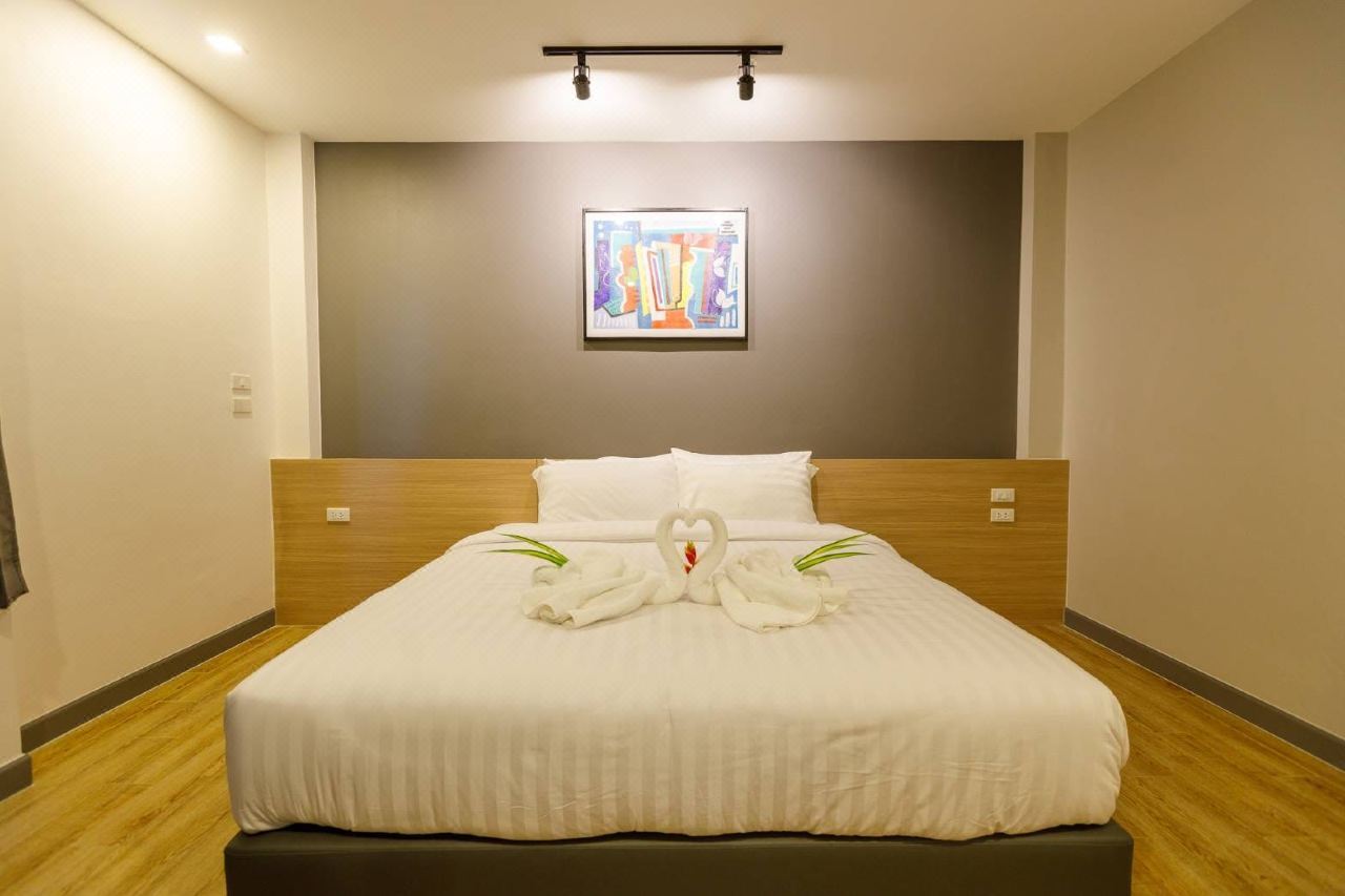 Warm-toned guest room with a King bed, white striped linen and two towels folded into swans